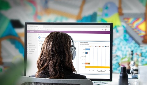 Eine Frau vor einem Bildschirm, von hinten fotografiert.