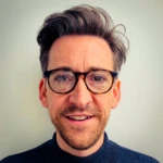 Stuart Almond wearing glasses and smiling at the camera