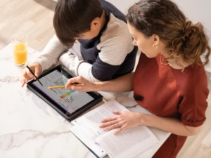 A mother helps her son with remote learning tasks.