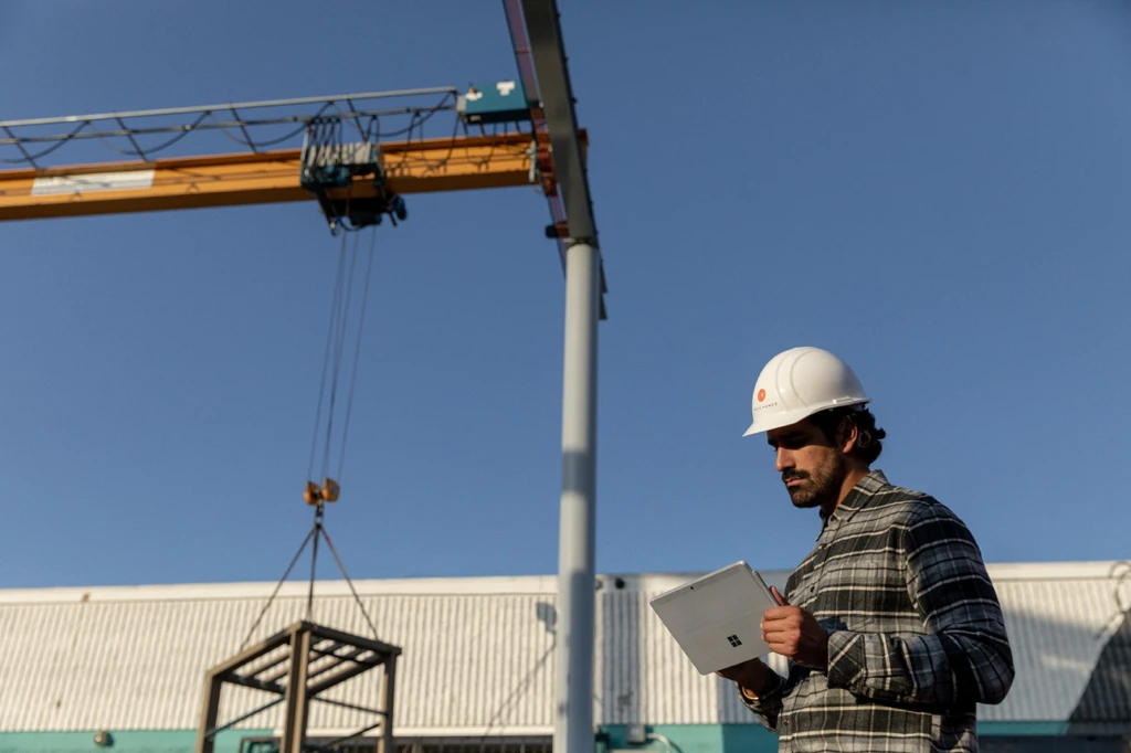 A frontline employee on a construction looks at a laptop for project management