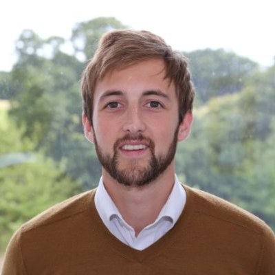 George Tbb, a man smiling for the camera with brown hair and a beard.