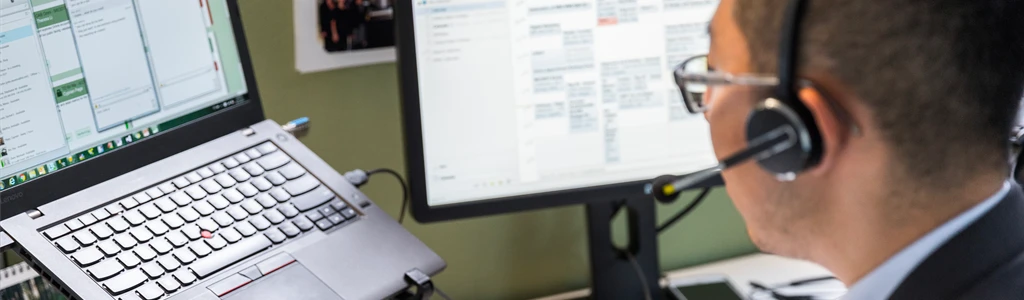 Pessoa em um escritório trabalhando com dois computadores