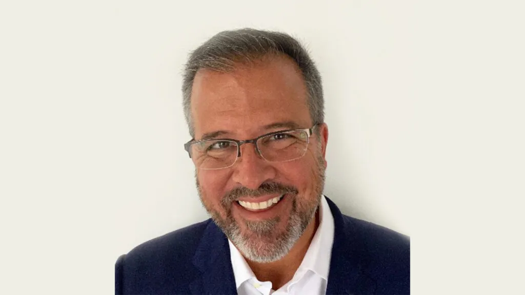 a man wearing a suit and tie smiling at the camera