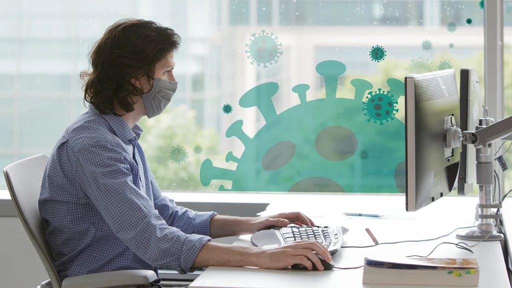a man with a mask working on a laptop