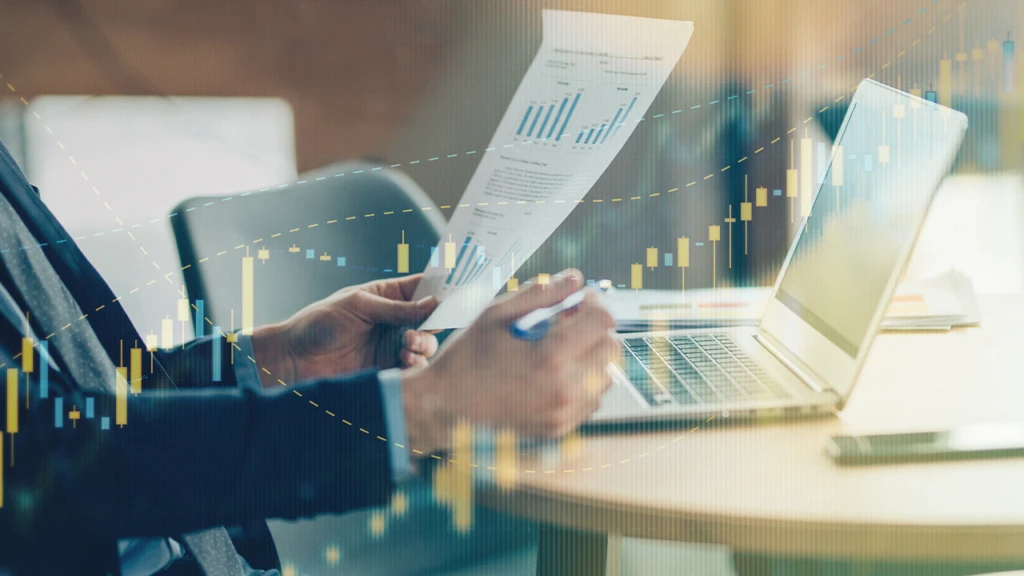 mage of a hand holding a piece of paper next to laptop
