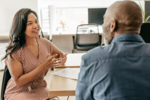 A recruiter interviews a job applicant in an open office space.