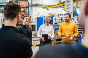 A group of employees converse on the floor of a factory
