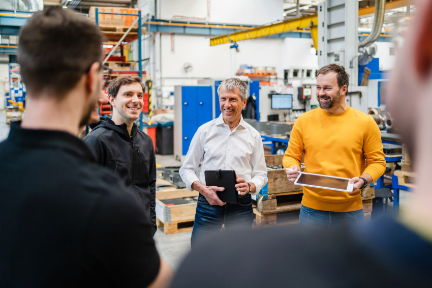 A group of employees converse on the floor of a factory