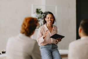 A woman holding a tablet and talking to a group of people