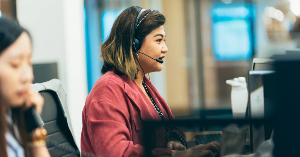 A woman wearing a headset and looking at a computer