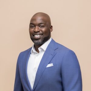 Person wearing a suit against a plain background