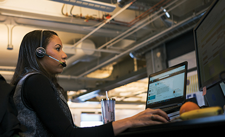 Image of a firstline worker working at her desk, answering a call on her headset.