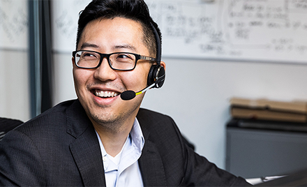 On office worker wearing a headset turns his head to react to a coworker.