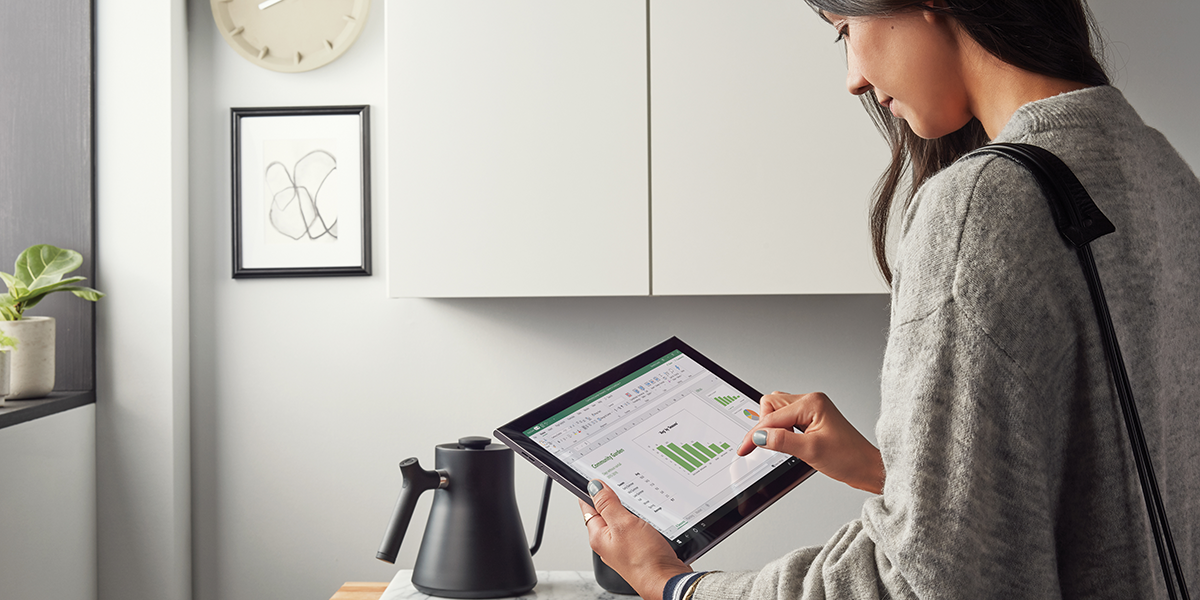 Image of a woman looking at an Excel graph on her tablet.