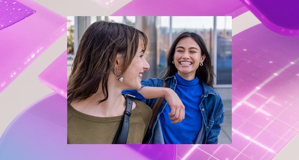 Two women smiling at each other while walking. The image is overlaid on a purple abstract background.