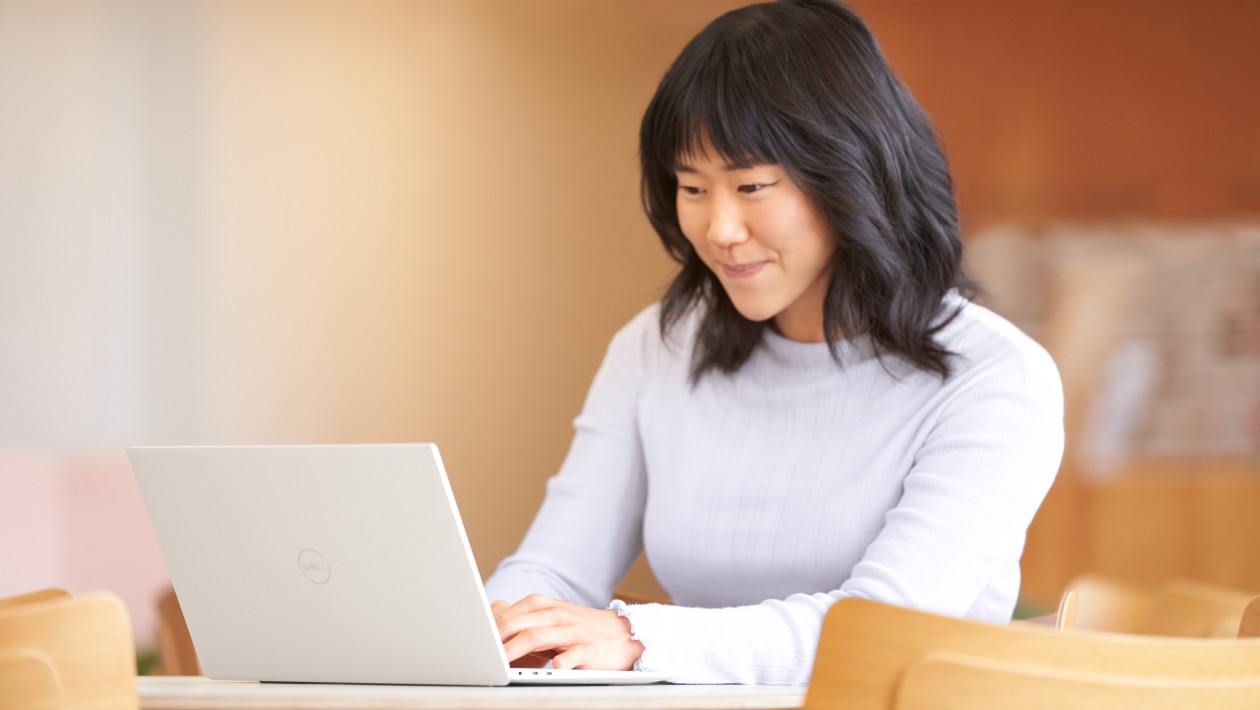 Woman smiling and engaged at laptop on desk.