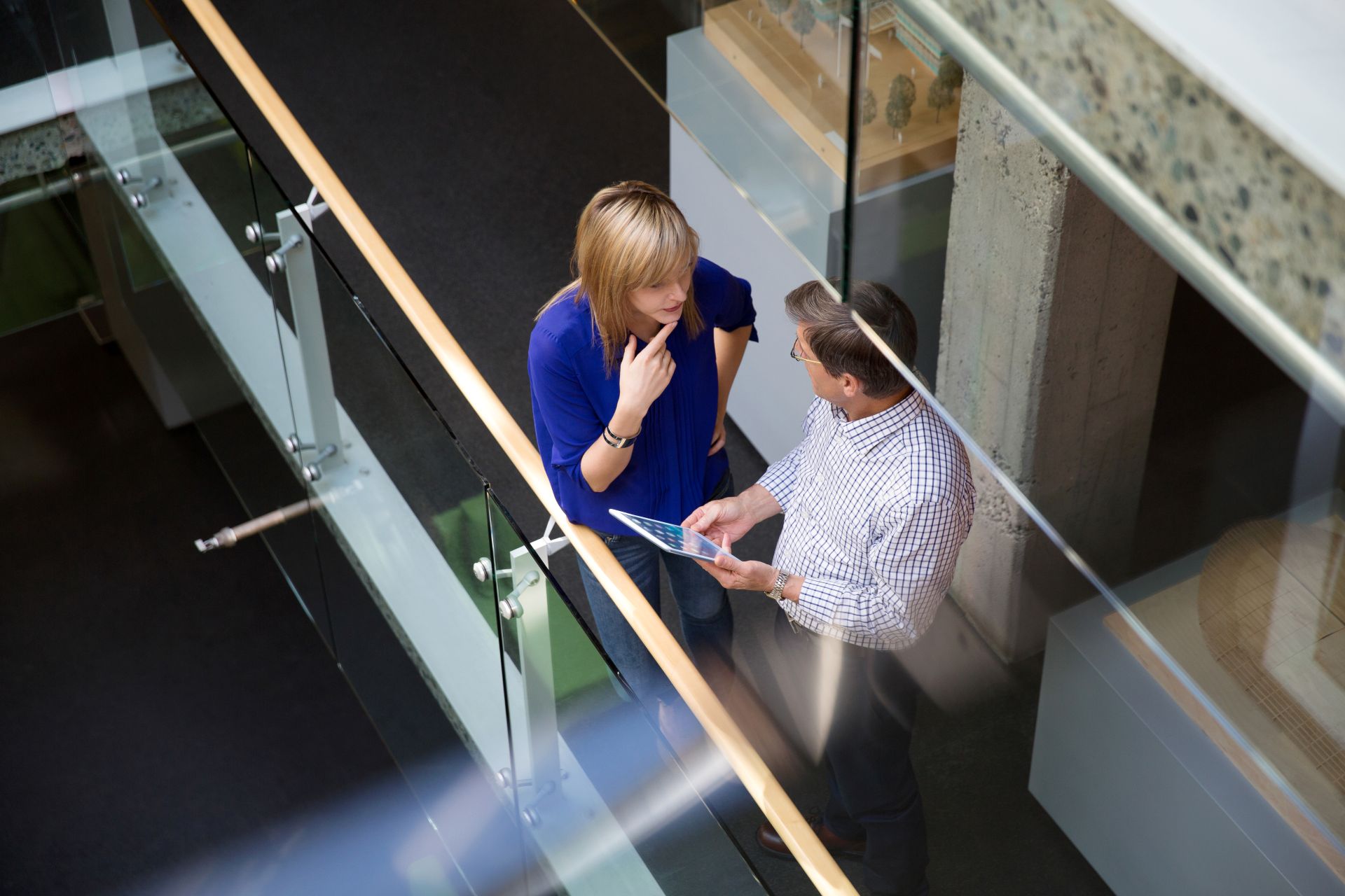 Overhead view of two professionals having a conversation in the hallway of a modern office