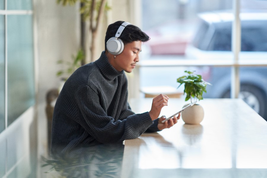 Customer using a tablet while wearing headphones and working securely remote from a café.