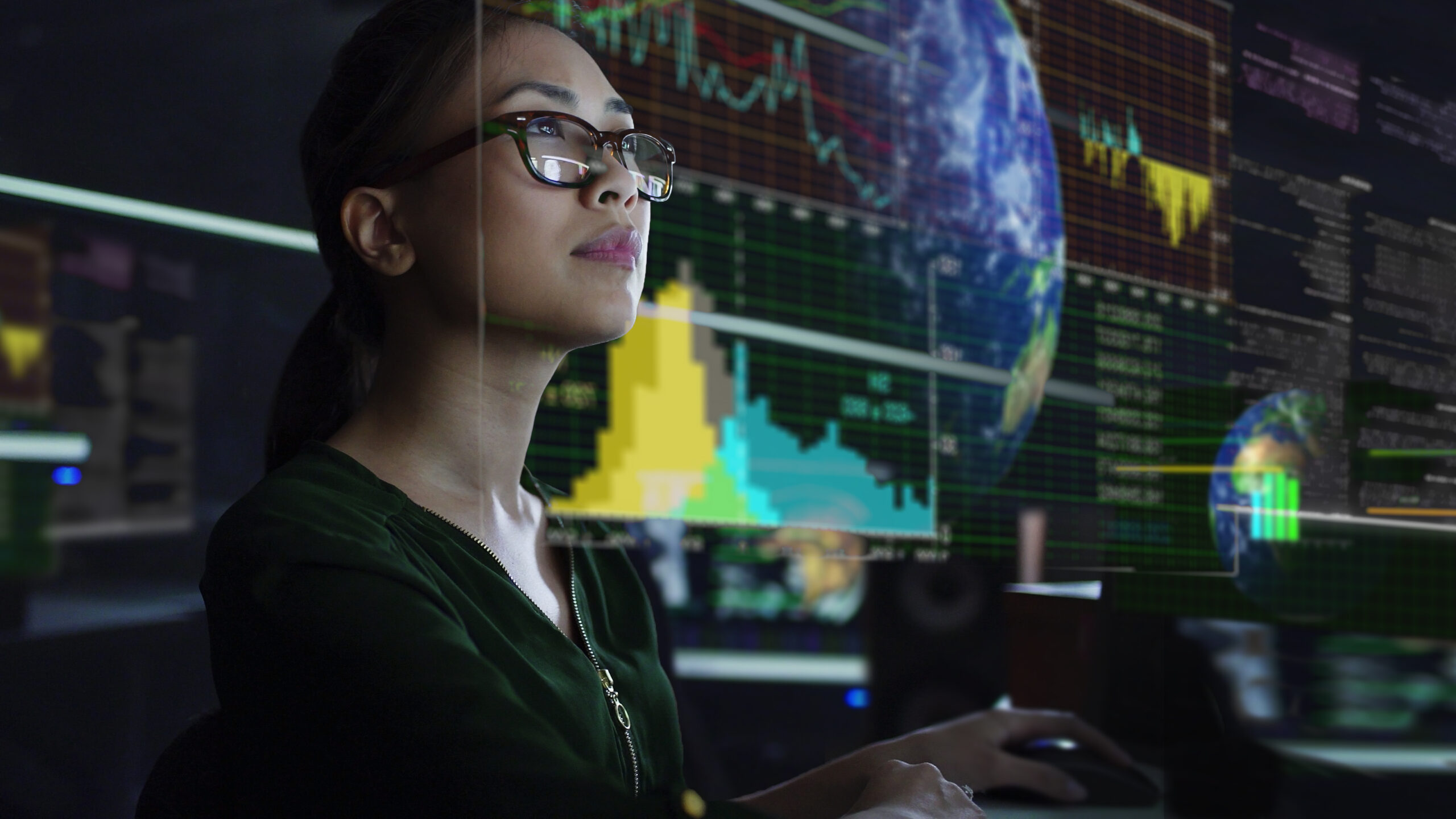 A woman analyzing sustainability data graphs on an oversized monitor, in a data command center