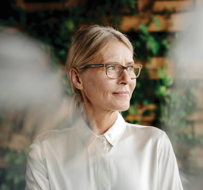 Profile image of person sitting in front of a wall of plants