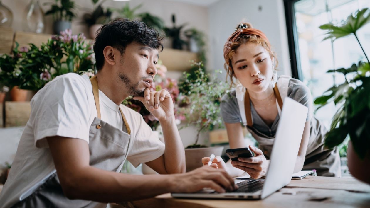 A man and woman looking at a laptop in a flowershop.
