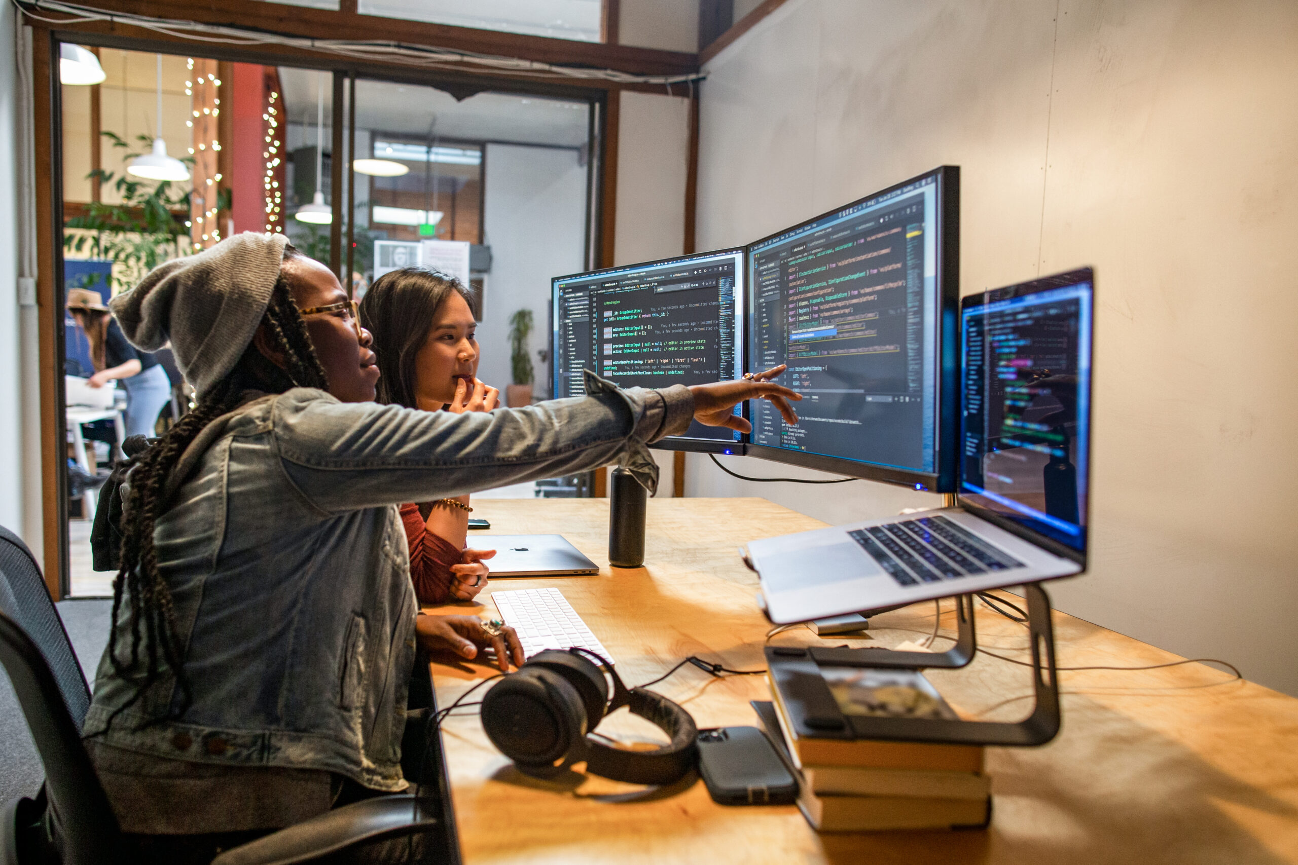 two people sitting in front of the computer and looking at the code