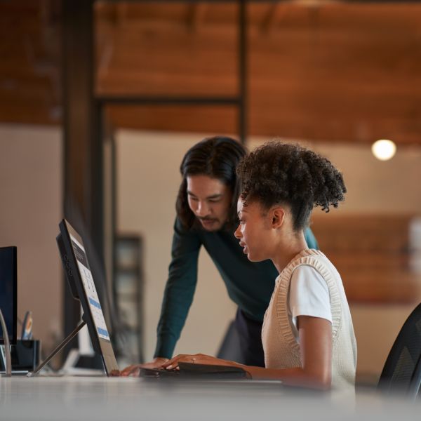 Two business professionals looking at a computer screen and collaborating in an office setting.