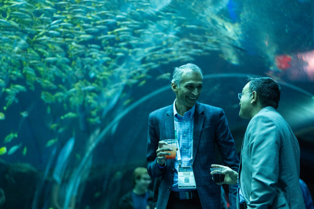 Attendees talking, aquarium in background.