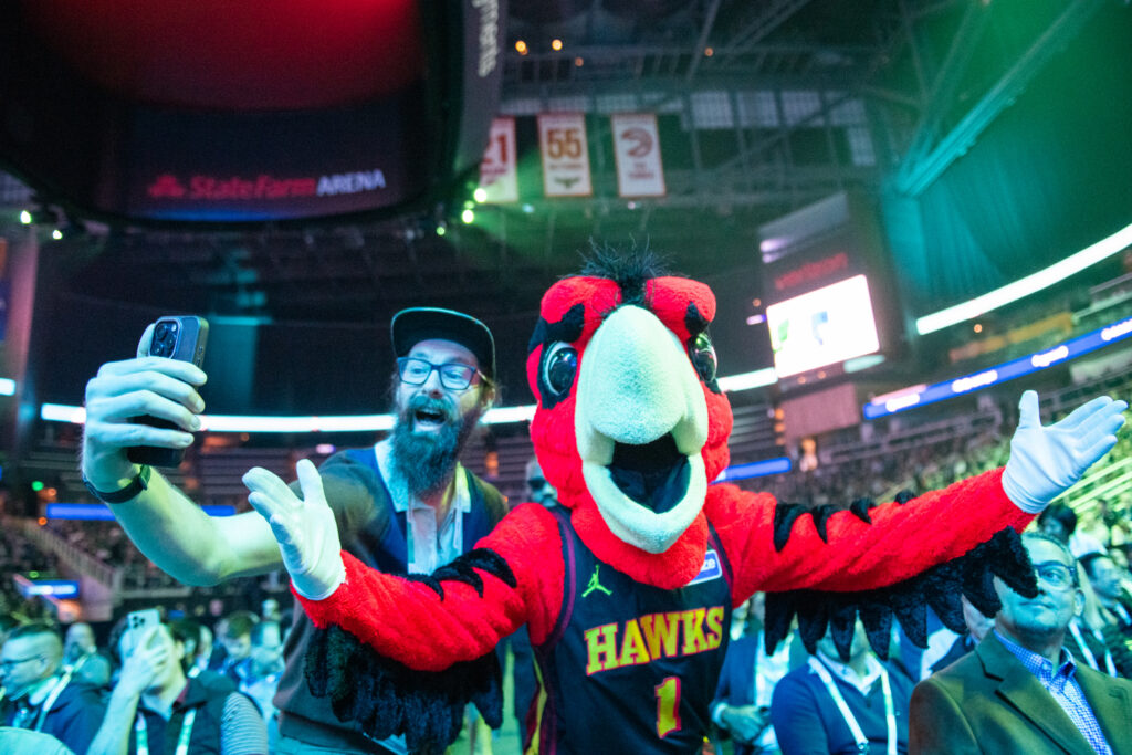 Attendee taking selfie with the Atlanta Hawks mascot.