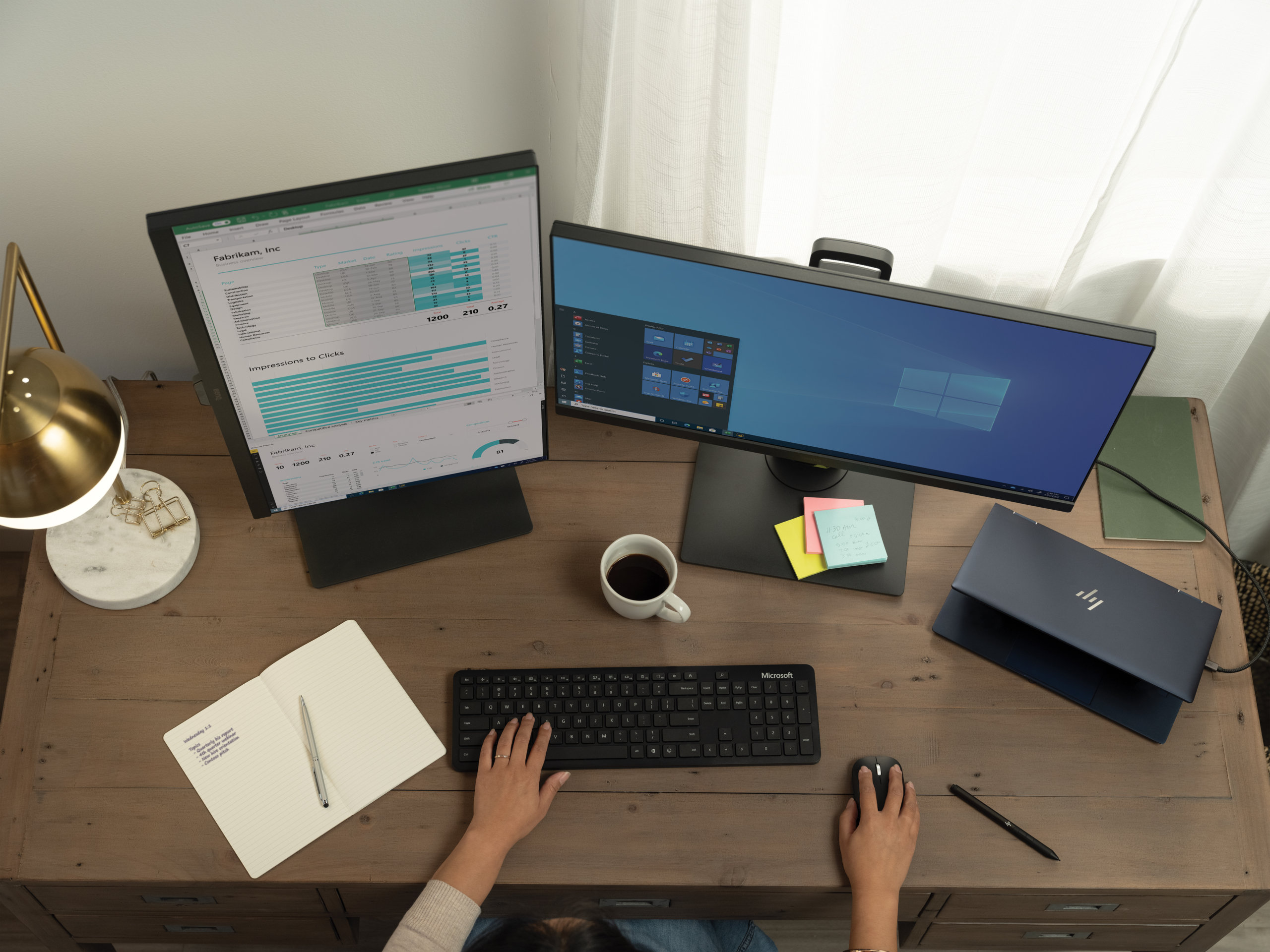 High angle view of a woman (hands only) working from home on her HP Elite Dragonfly configured with a multi-monitor setup displaying Excel, Pwer BI and Windows Start menu. Remote Working collection. Keywords: remote work, remote working, work from home, working at home, home office