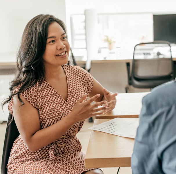 A recruiter interviews a job applicant in an open office space.