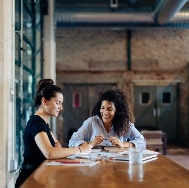 Two businesspeople talking at conference table in a loft office.