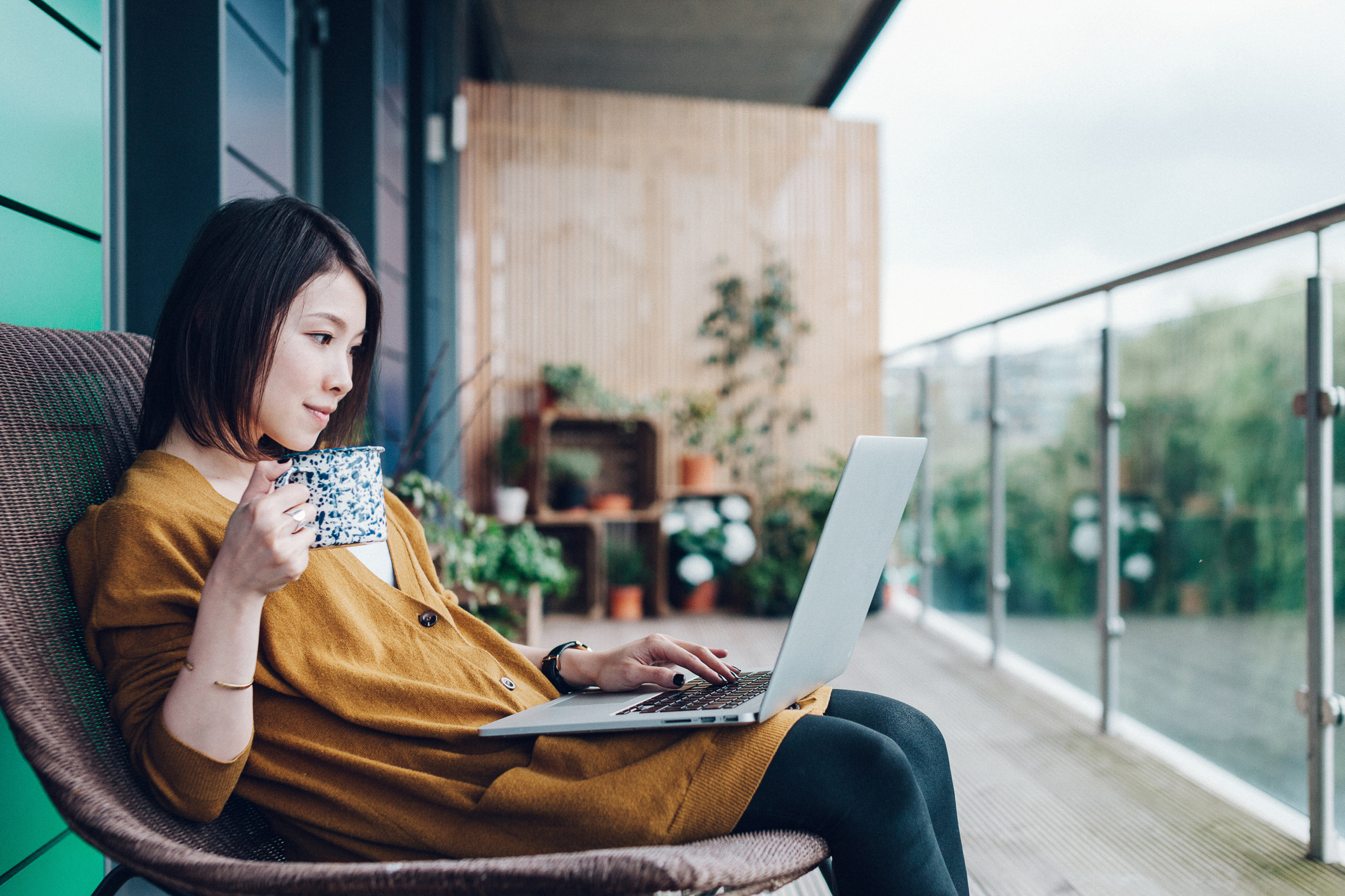 A woman sitting on a chair with a laptop and a cup of coffee