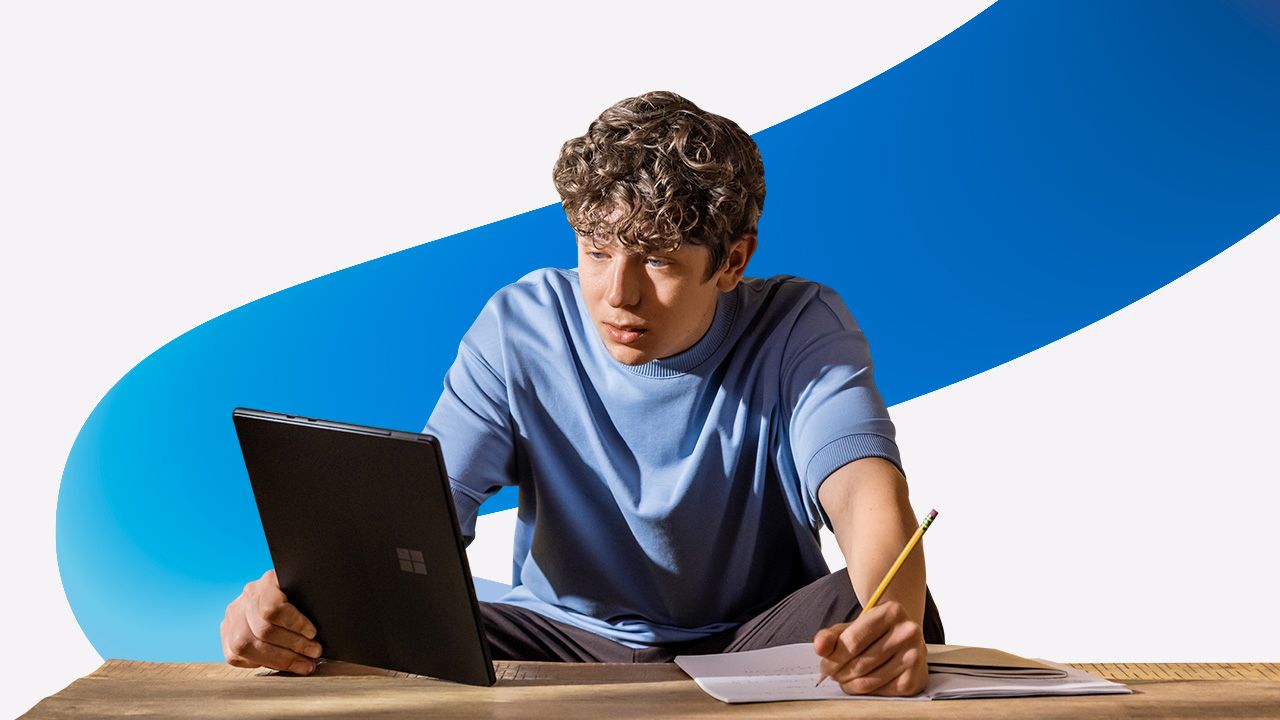 A man sitting at a table with a laptop and a pencil