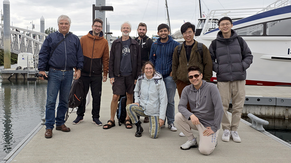 Ivan Tashev et al. posing for a photo next to a boat