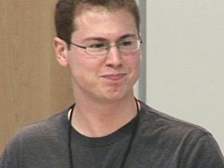 a man wearing glasses and smiling at the camera