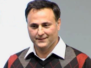 a man wearing a suit and tie smiling at the camera