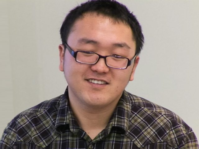 a man wearing glasses and smiling at the camera