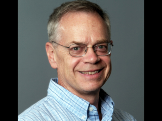 a man wearing glasses and smiling at the camera