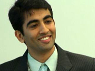 a man wearing a suit and tie smiling at the camera