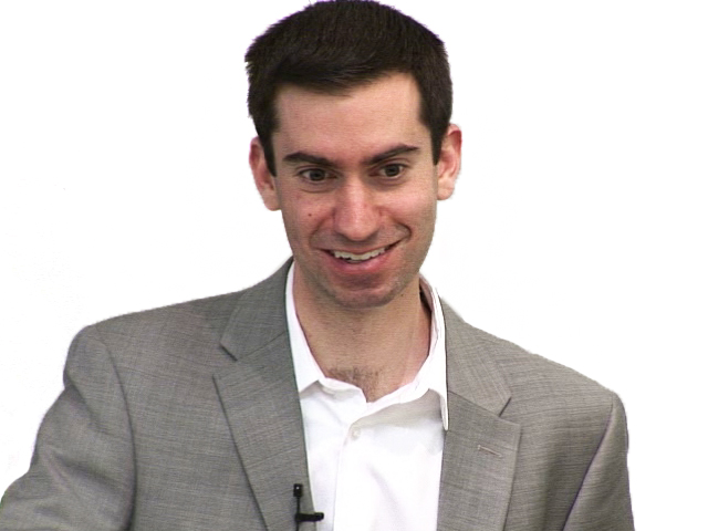 a man wearing a suit and tie smiling at the camera