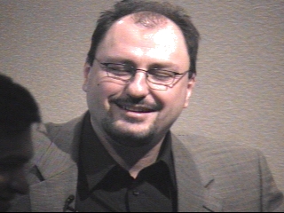 a man wearing glasses and smiling at the camera