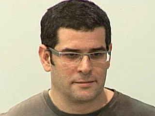 a man wearing glasses and smiling at the camera