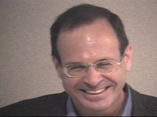a man wearing glasses and smiling at the camera