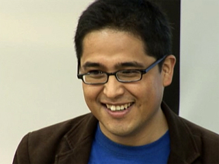 a man wearing glasses and smiling at the camera