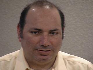 a man wearing a suit and tie smiling at the camera