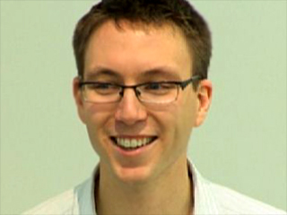 a man wearing glasses and smiling at the camera