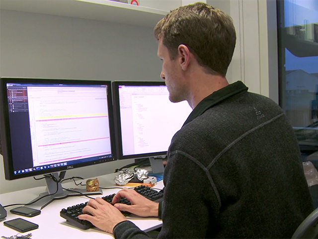 a man sitting at a desk with a computer monitor