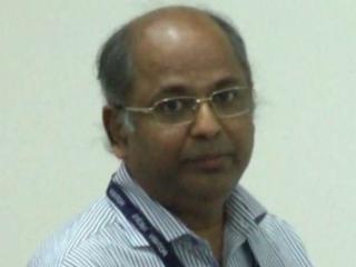 a man wearing glasses and smiling at the camera