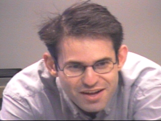 a man in glasses looking at the camera